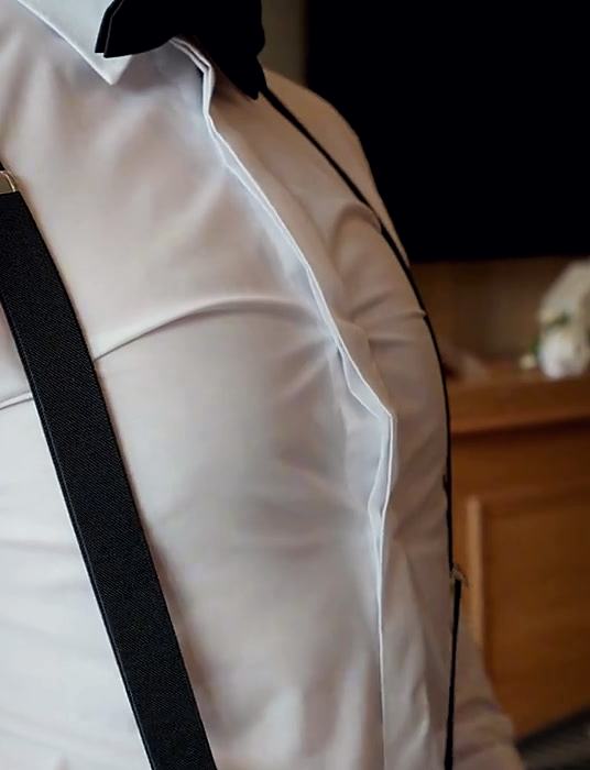 Braces being fitted over a pressed white dress shirt.