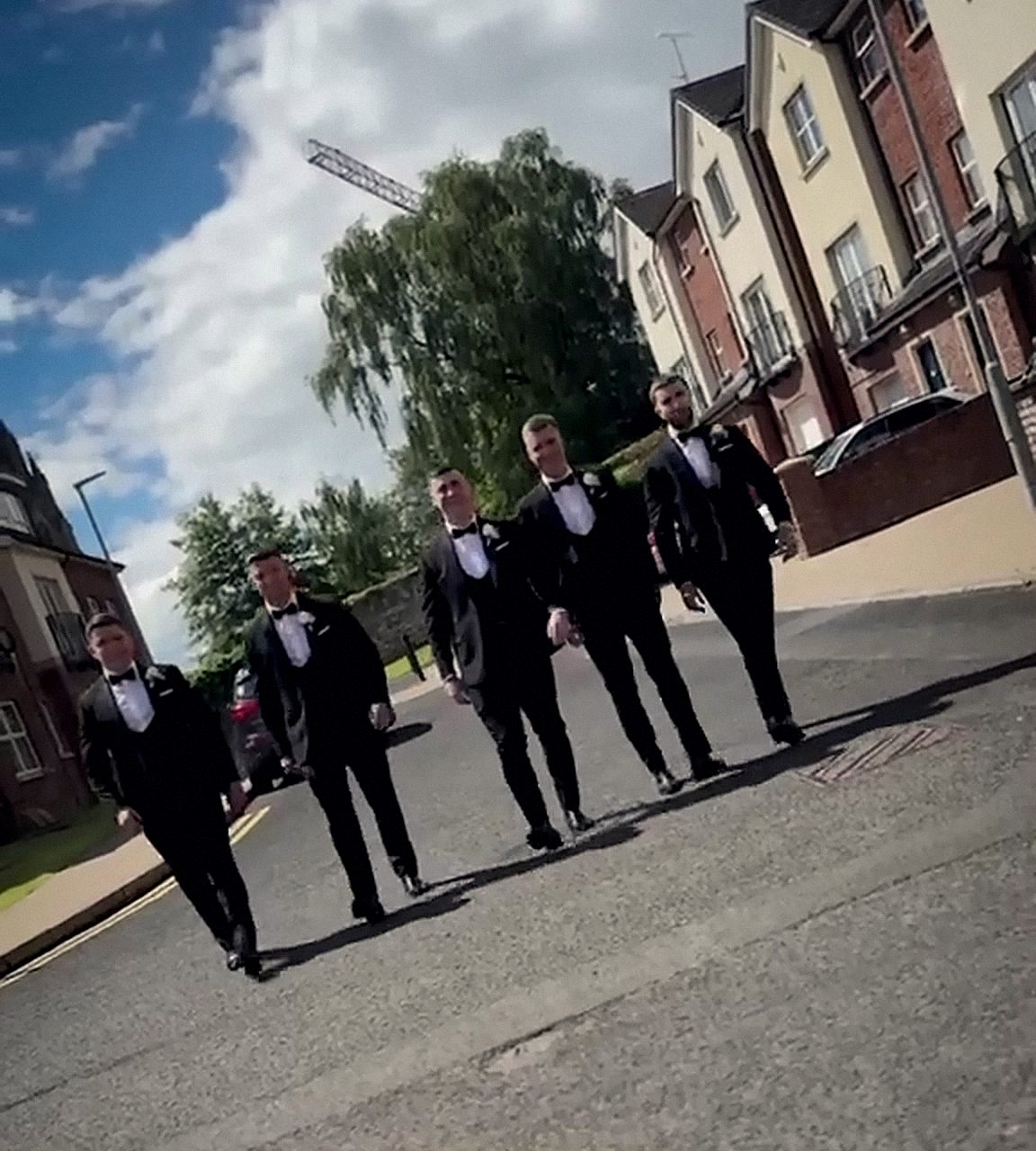 A wedding party in black tie walking out on the morning of the wedding.