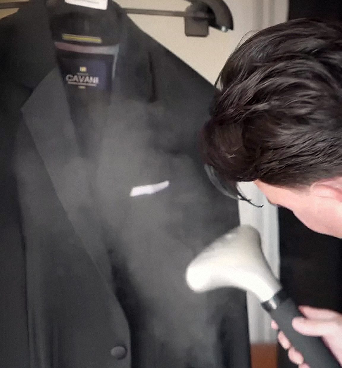 A jacket being steamed on a rail before a wedding.