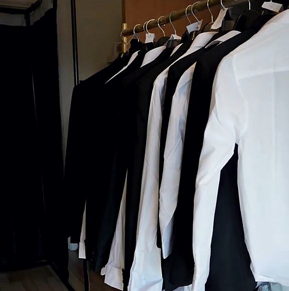 A travelling rail of pressed suits and shirts ready for a wedding party.